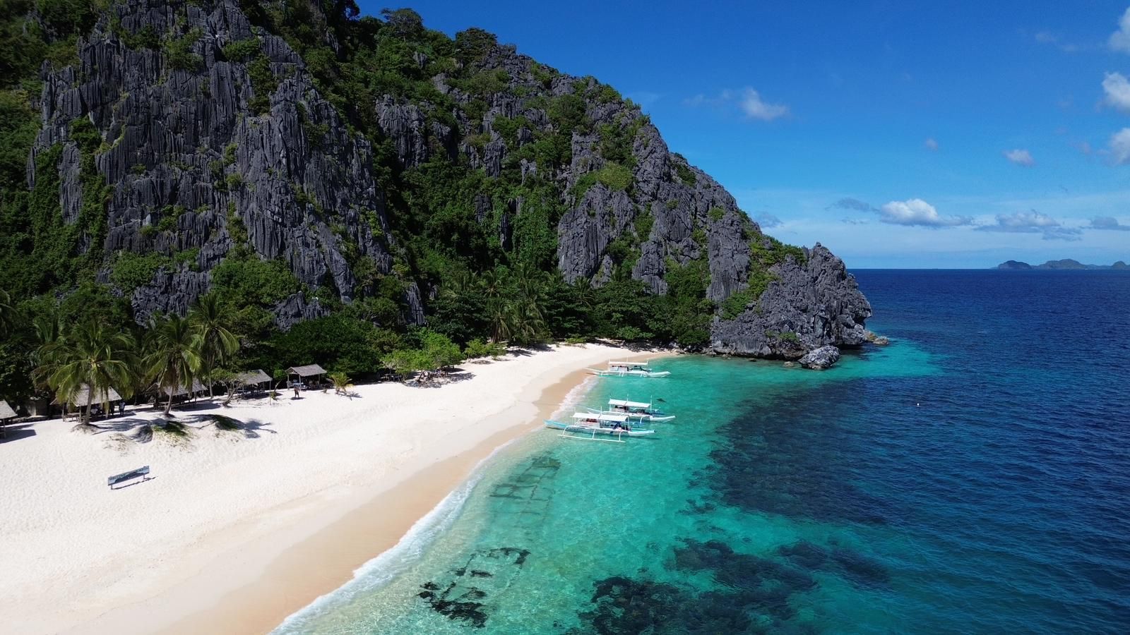 An aerial view of a tropical beach with boats in the water.
