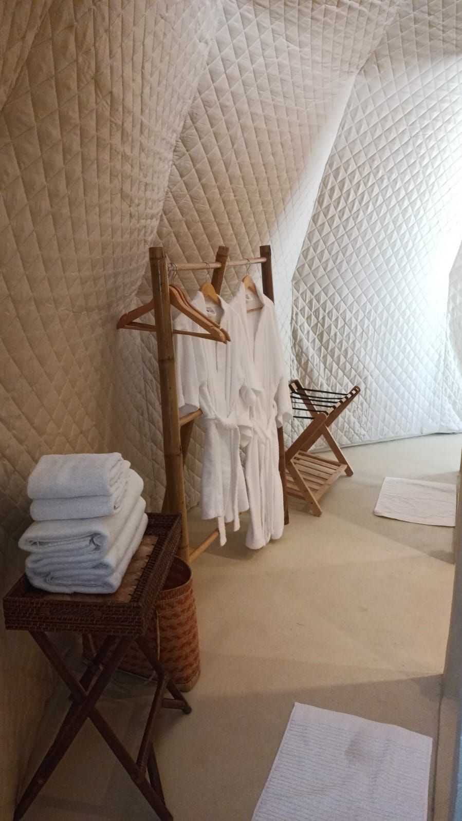 A bathroom with robes hanging on a rack and towels on a table.