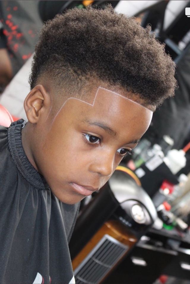 Boy with high top haircut and etched design on his forehead.