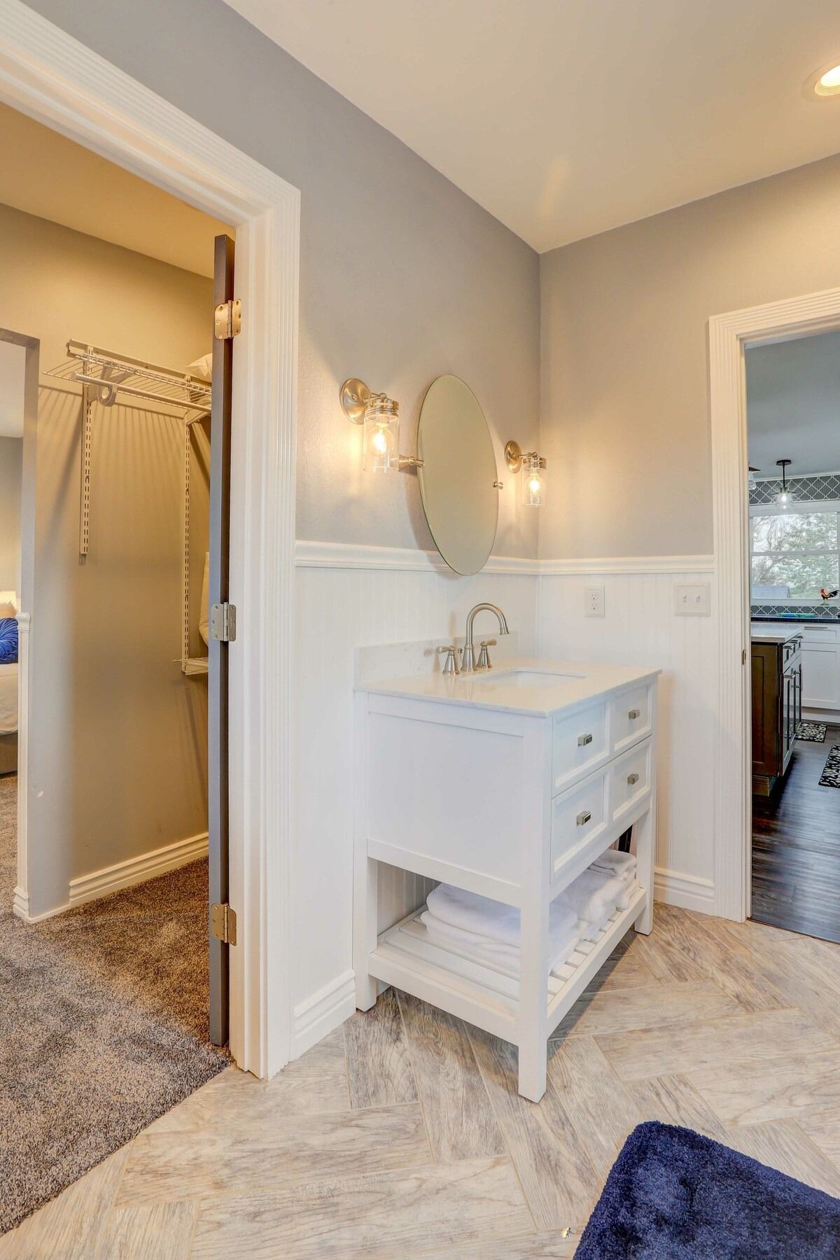 Small bathroom with white vanity, oval mirror, and open doorway to a shower area