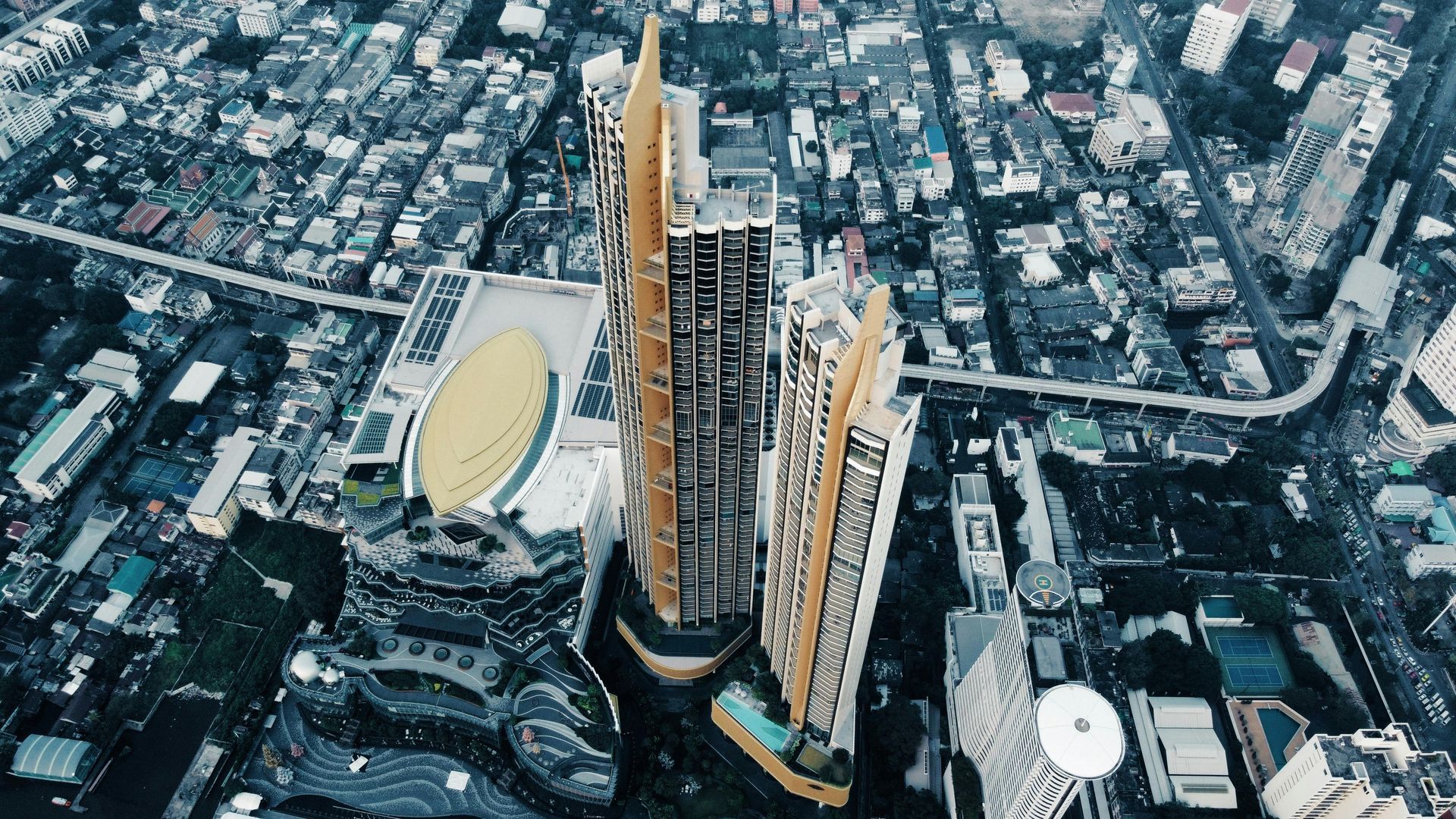 Aerial view of two tall skyscrapers with gold accents amidst a cityscape.