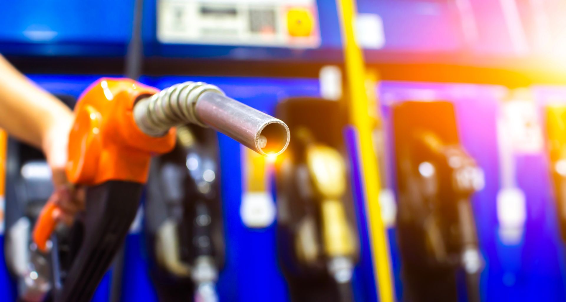 A person is pumping gas into an orange container.