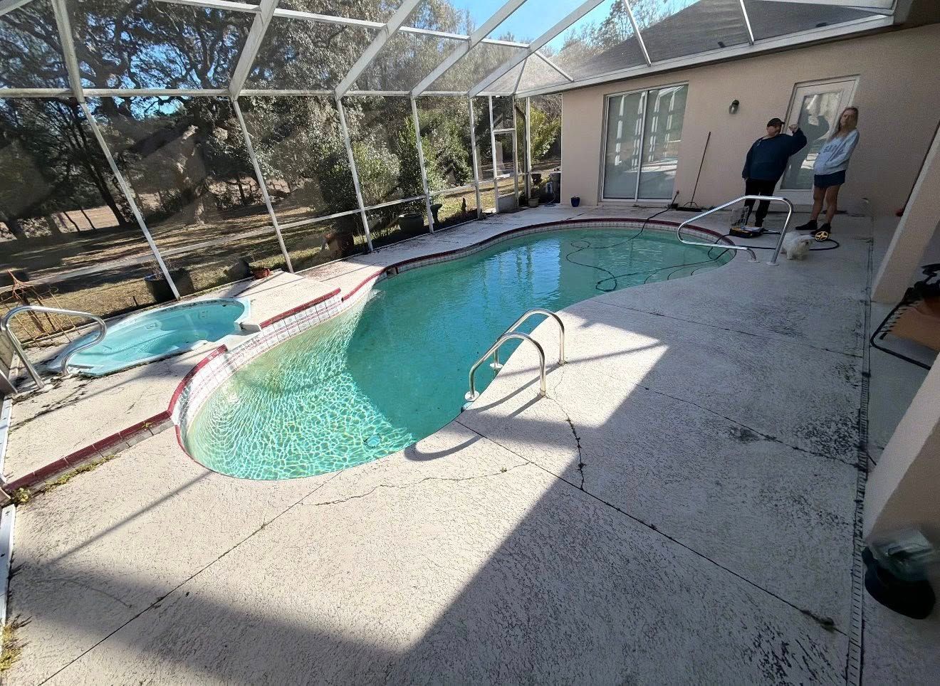 Backyard swimming pool beside a patio, with two people standing near the house.
