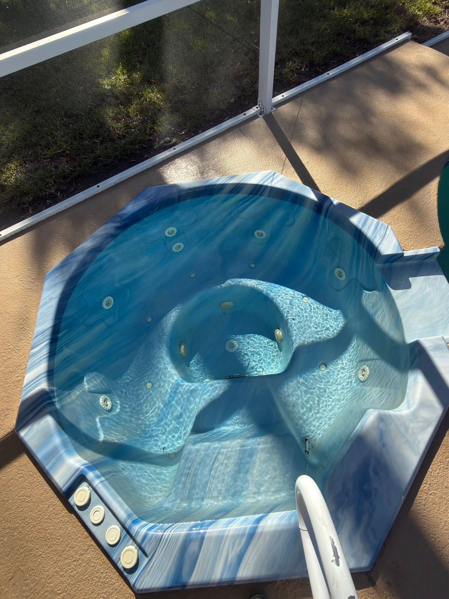 Blue inflatable hot tub on a sunlit patio beside a glass railing.