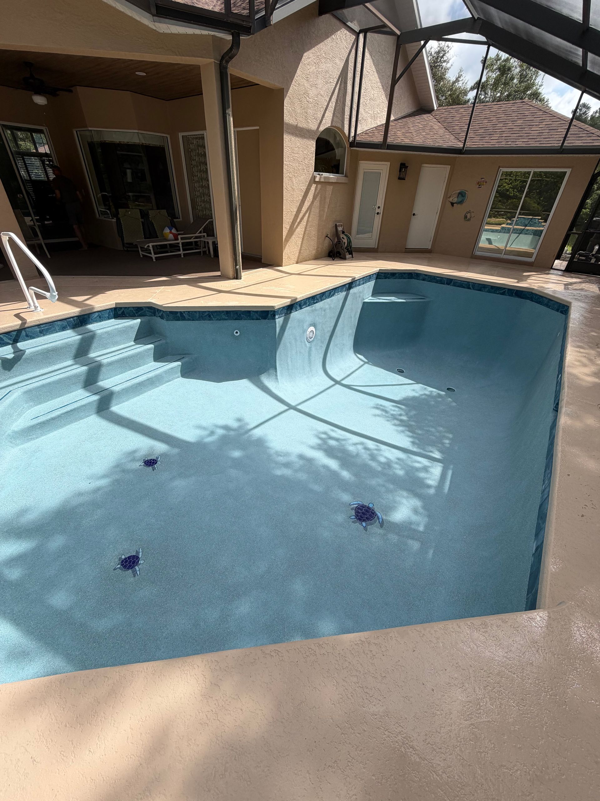 Backyard swimming pool with blue water, beige patio, and covered outdoor seating area