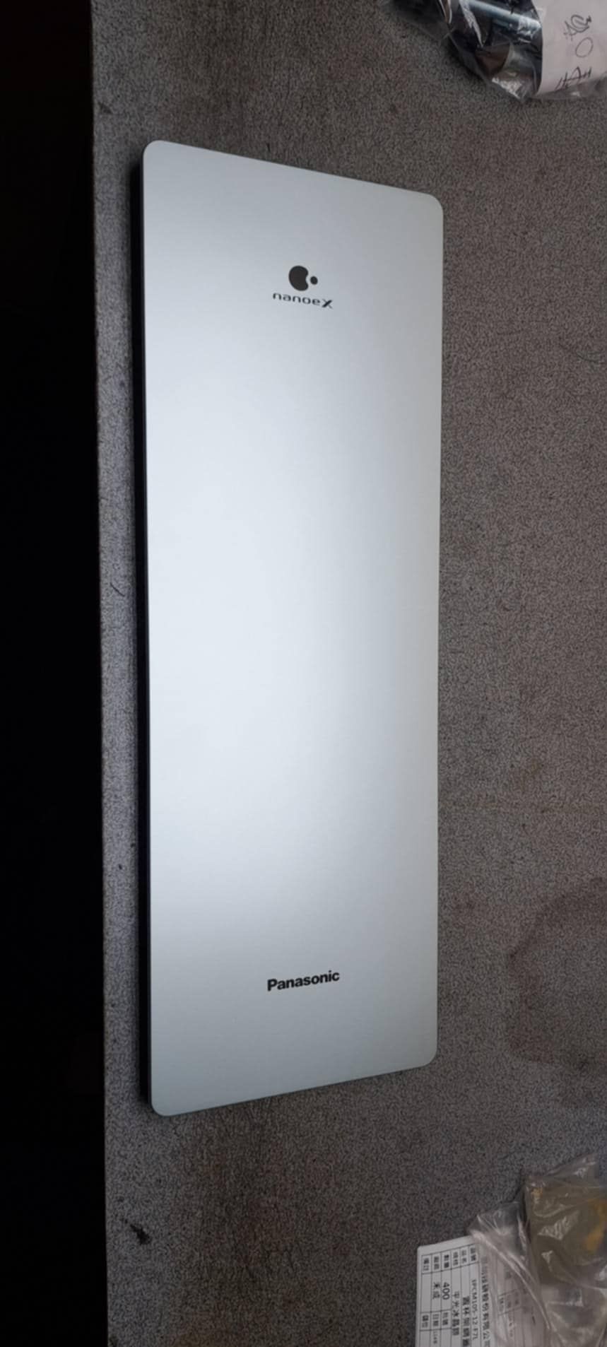 白色壁掛式電器，有一個小標誌，斜靠在鋪著地毯的地板上。