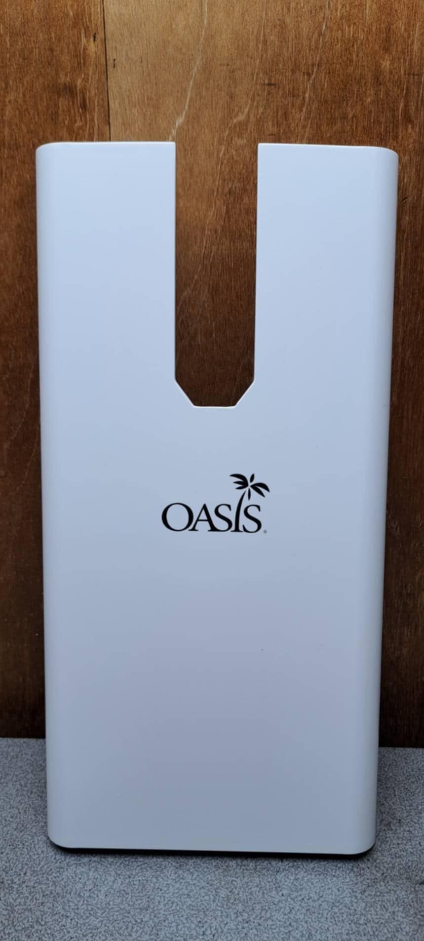 一張印有 Oasis 品牌標誌的白色卡片，帶有 U 形缺口，豎立在木質背景上。