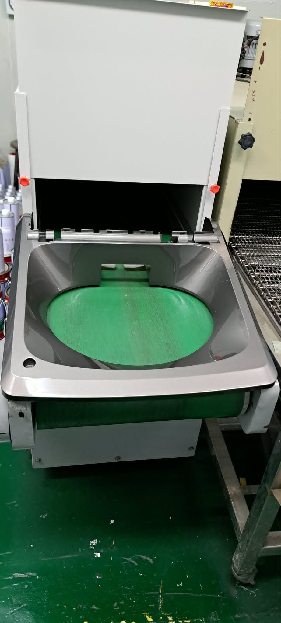 打開工業機器，金屬腔室內有一個綠色圓形托盤。