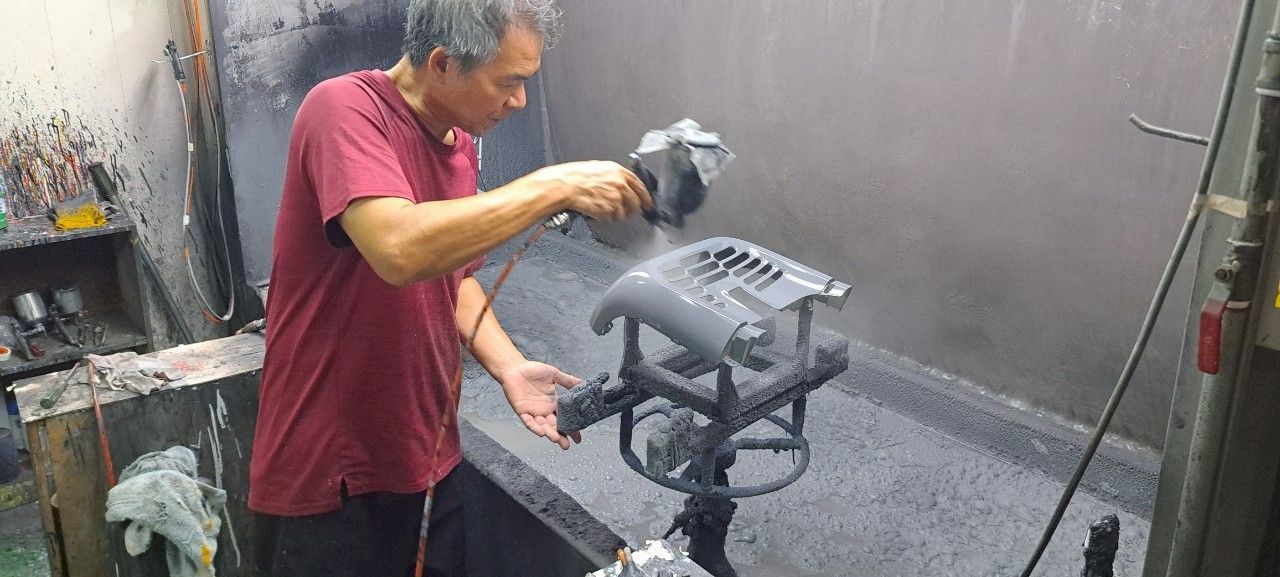一名男子在車間裡幫金屬椅噴漆。