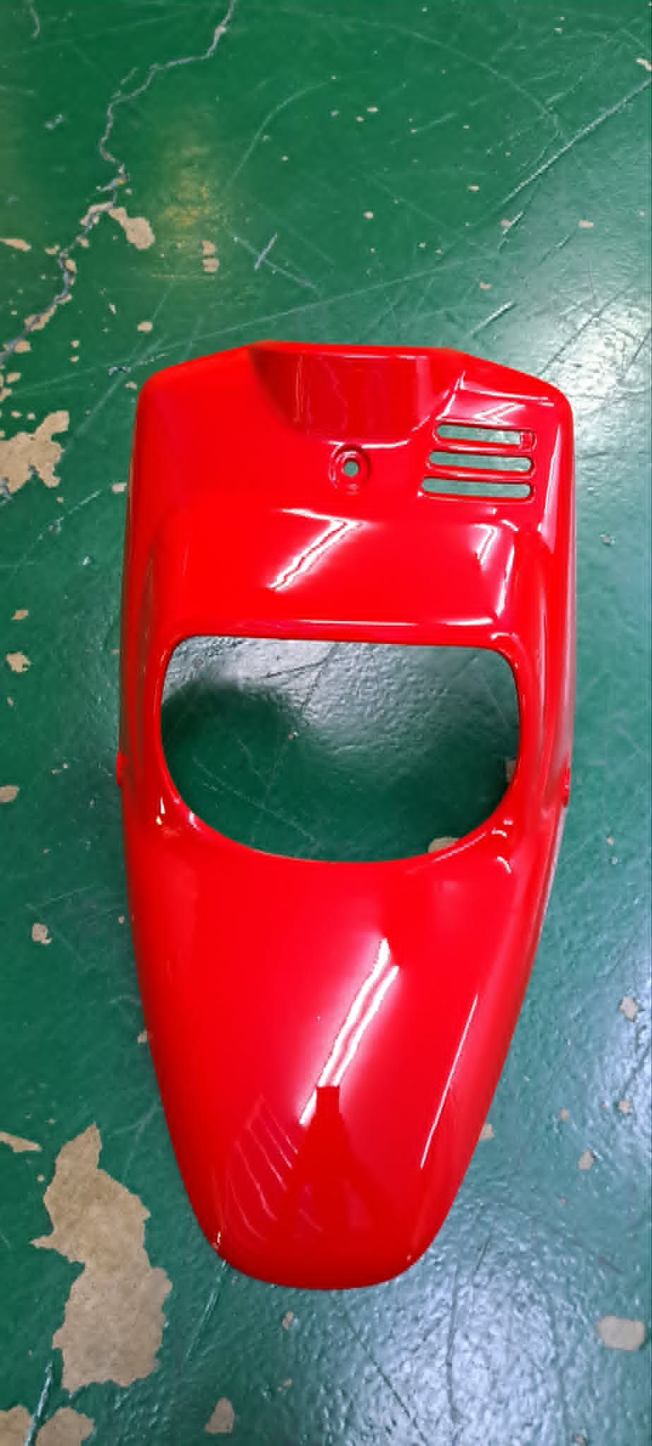 從上方俯視，綠色地板上有一個紅色塑膠汽車外殼玩具。