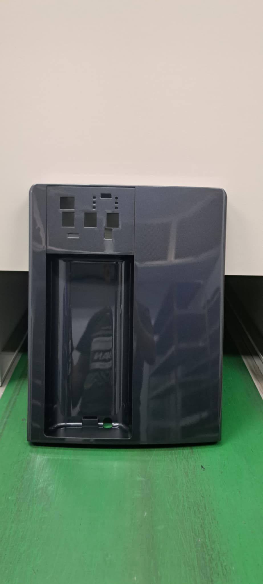 一台深灰色桌上型電腦主機放在綠色桌面上，背景是米色牆壁。