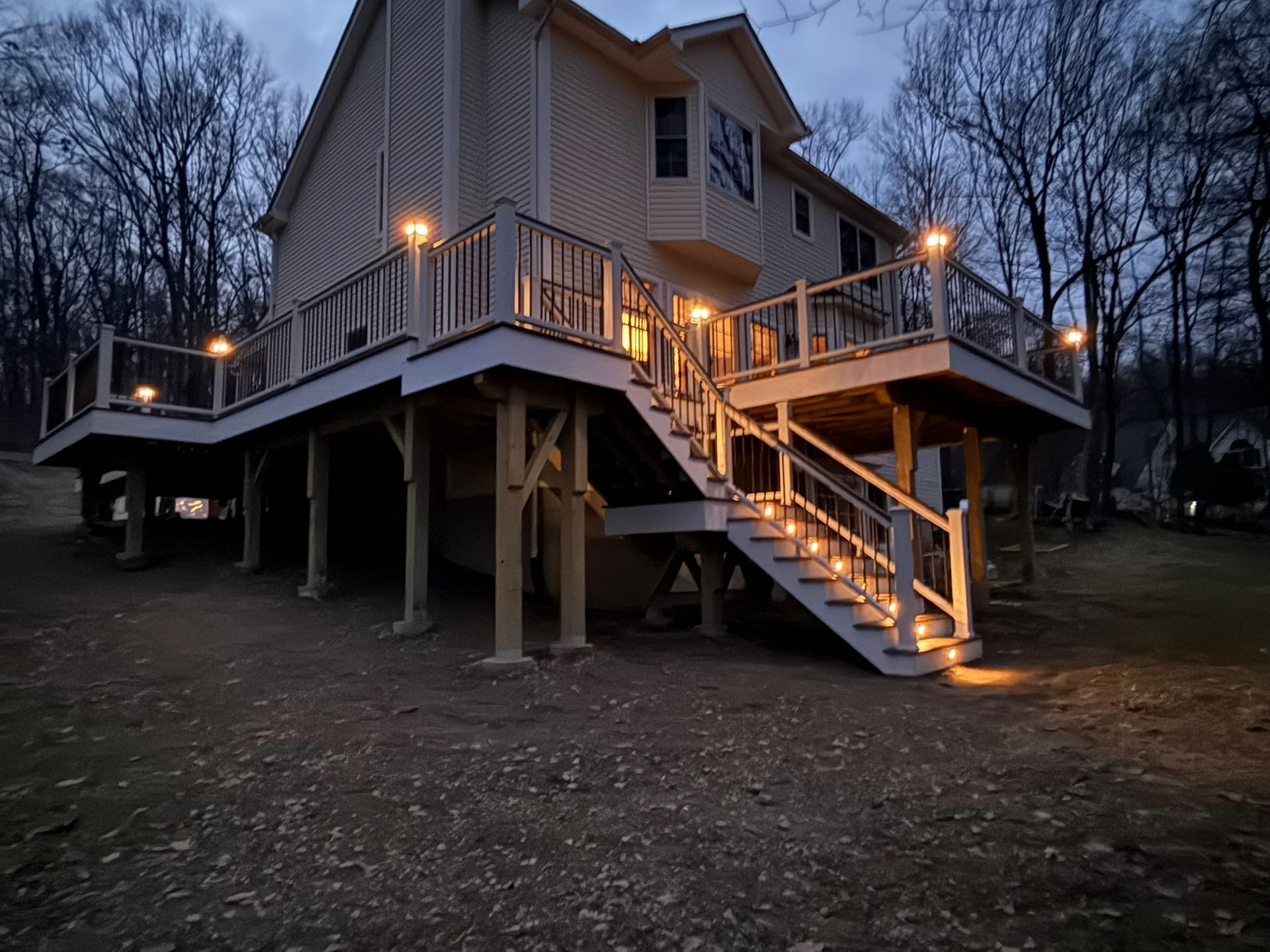 Wooden deck with white railing and black metal balusters overlooking a suburban front yard and street.