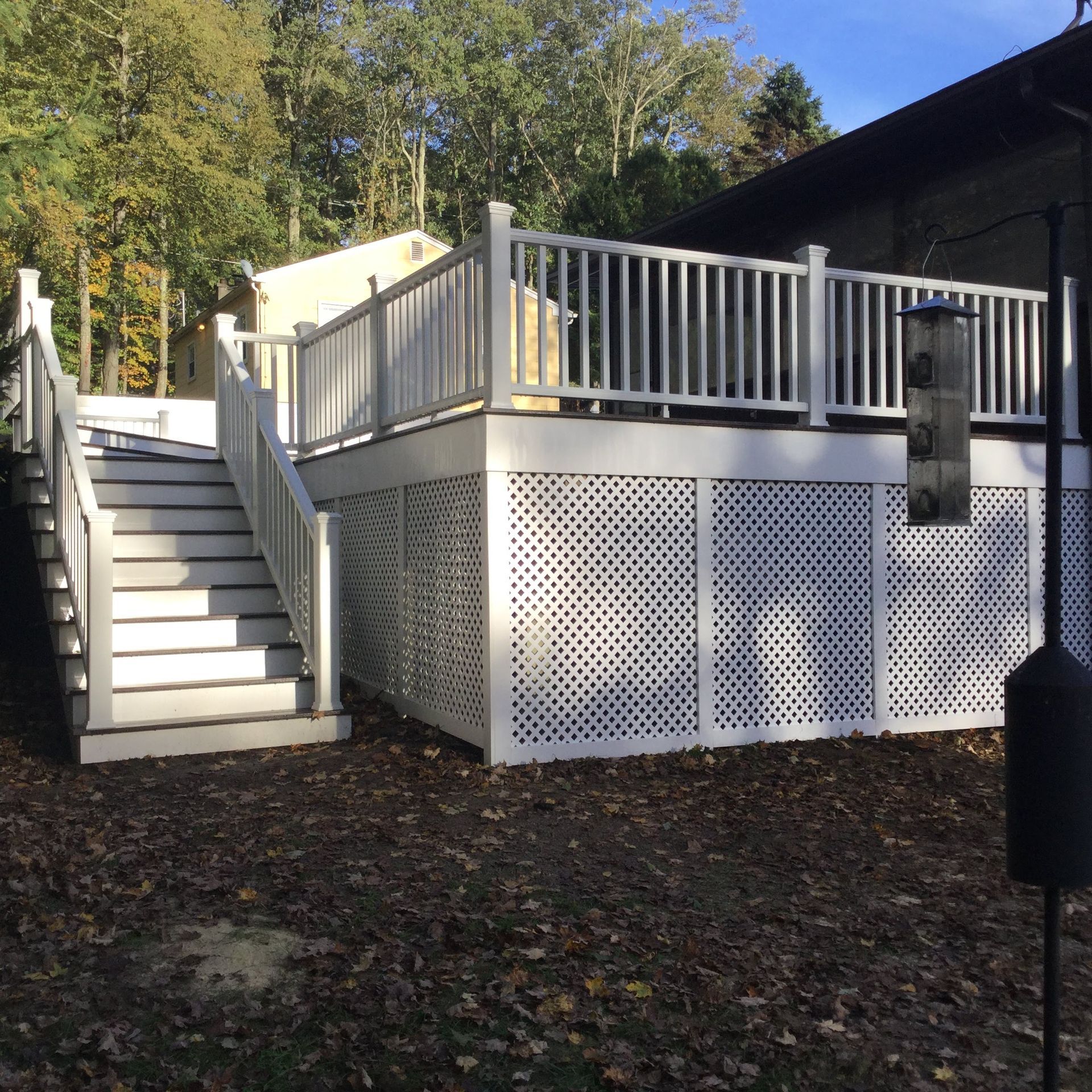 Back patio with wooden deck, pergola, white columns, and outdoor seating beside a house