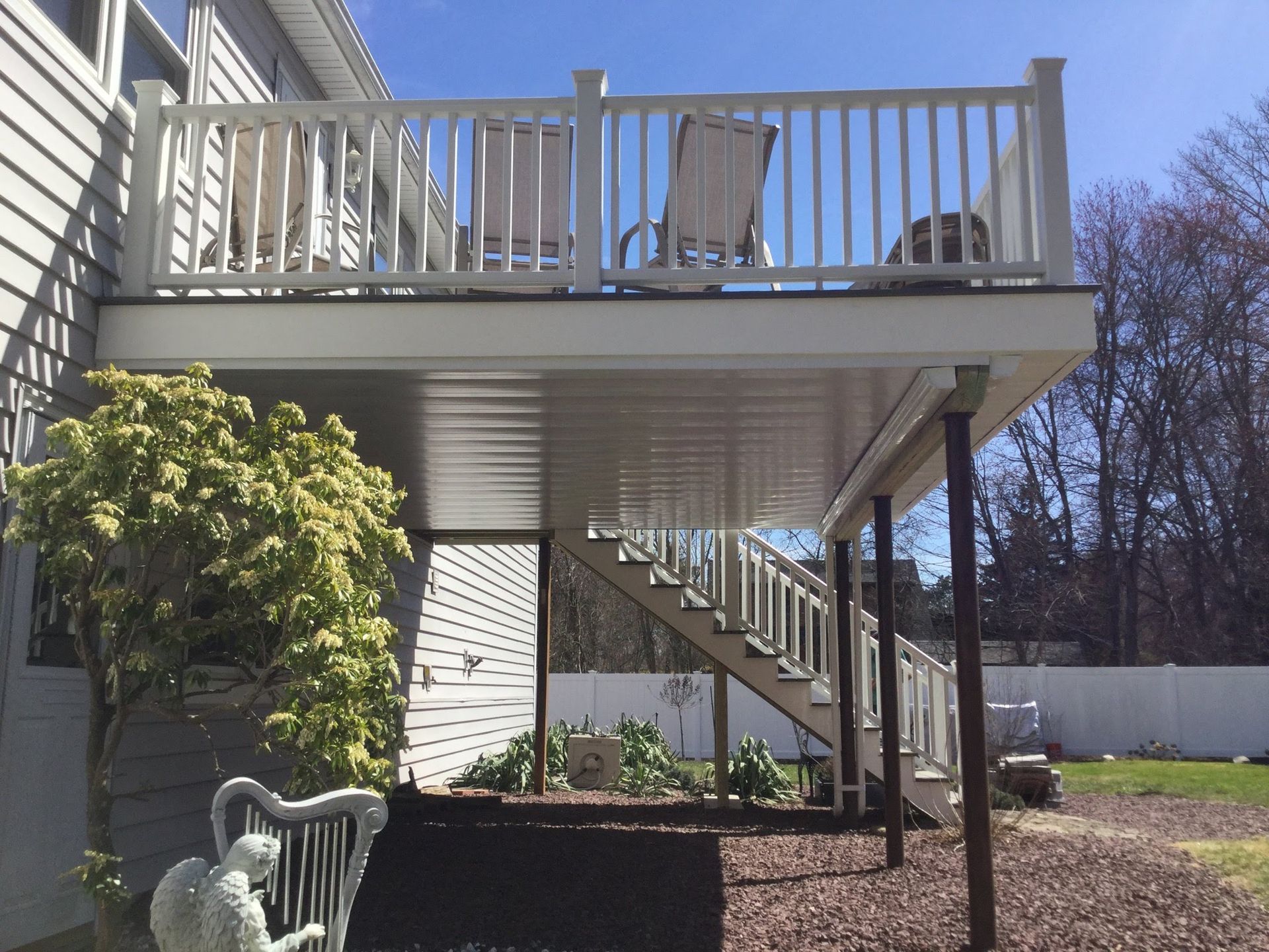 Wooden deck with white railing and black metal balusters overlooking a suburban front yard and street.
