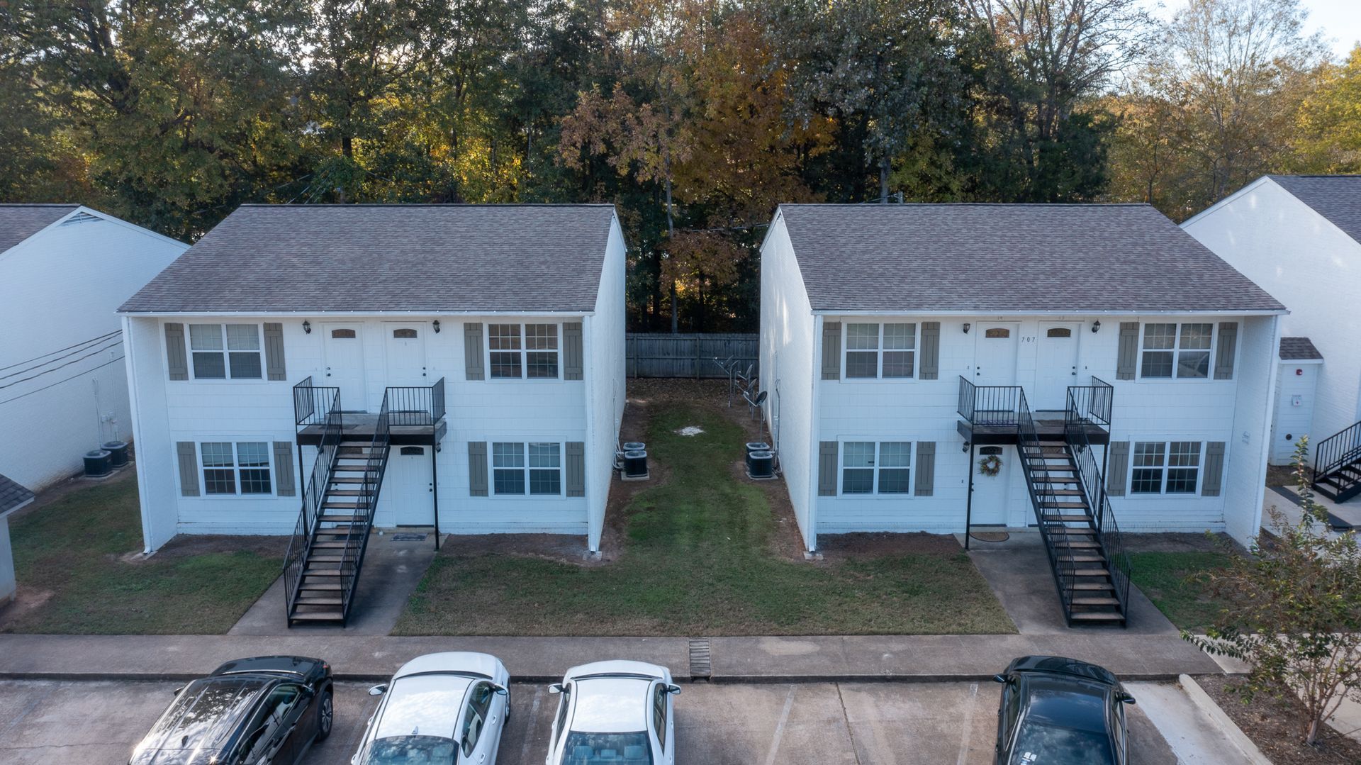 a row of white houses with cars parked in front of them