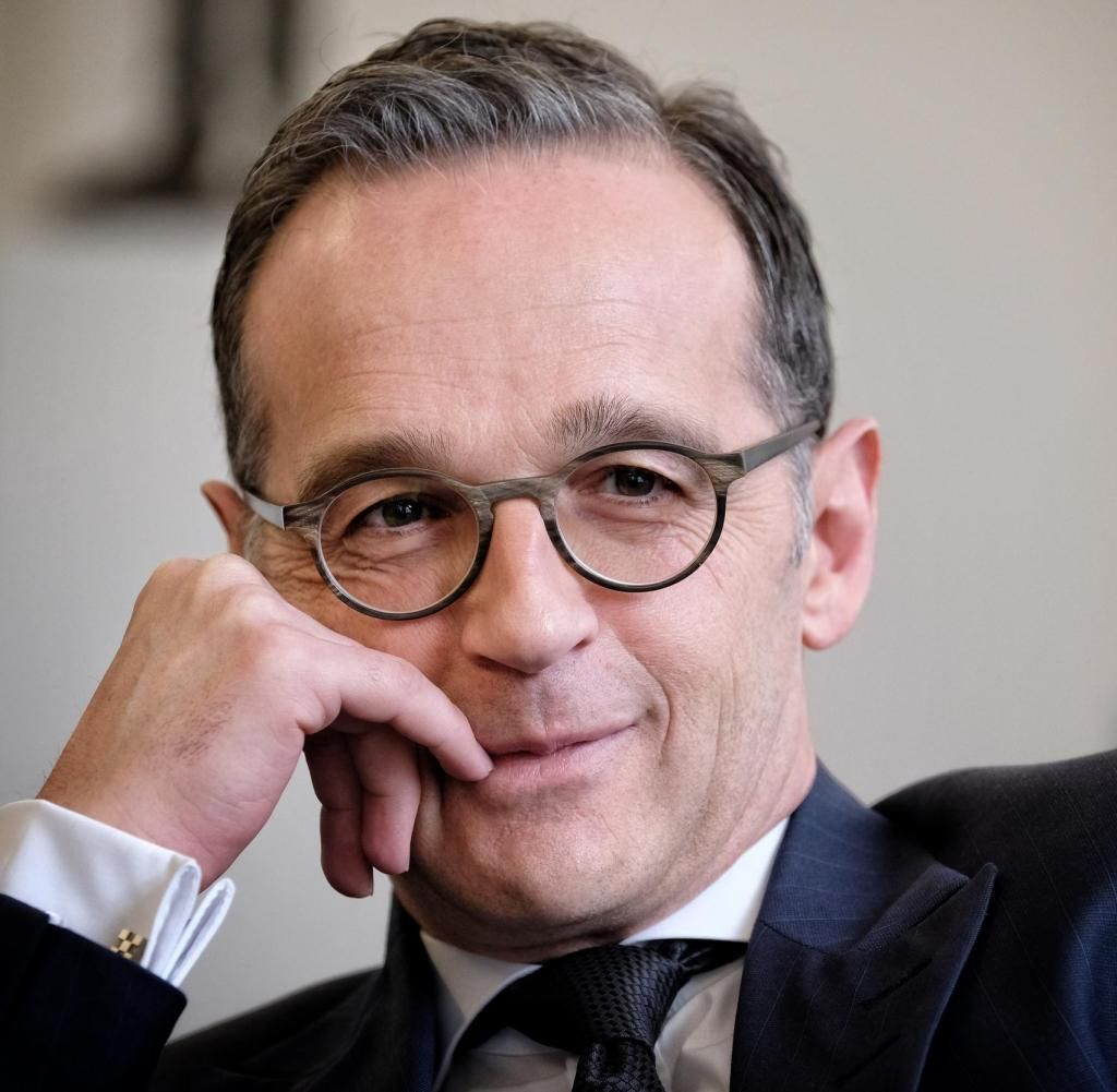 Mann mit Brille, der sein Kinn auf die Hand stützt und leicht lächelt.