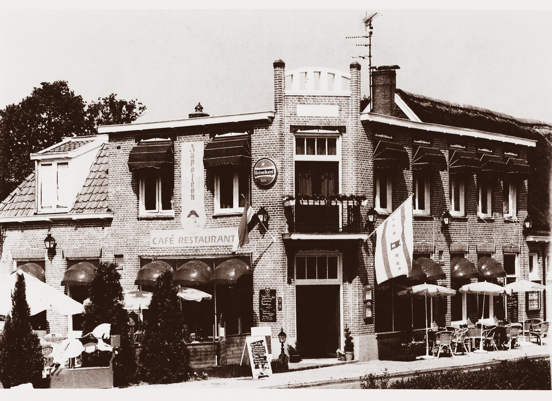 Café-restaurantgebouw met luifels, vlag en terras.