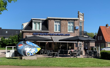 Cafégebouw met terras en een kleurrijke kunsttentoonstelling aan de voorkant.