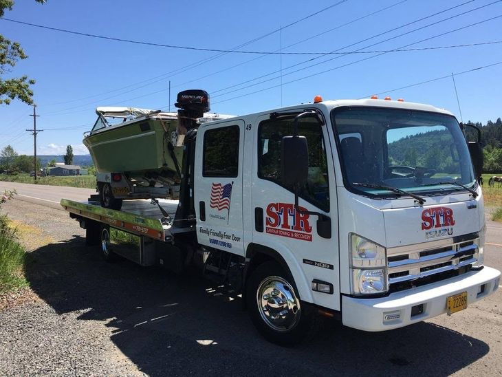 White STB utility truck carrying green equipment on a roadside under a clear blue sky.