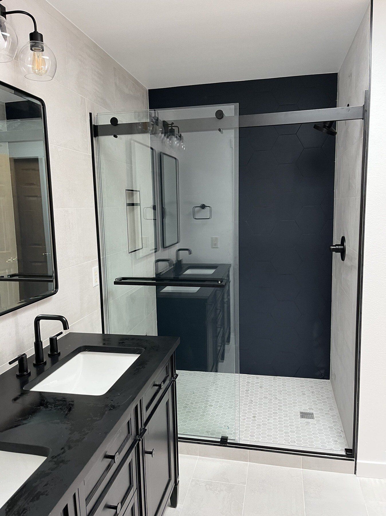 A bathroom with two sinks and a walk in shower.