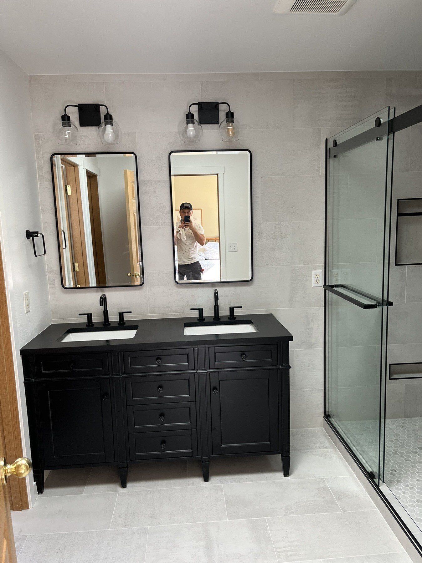 A bathroom with two sinks , a mirror and a shower stall.