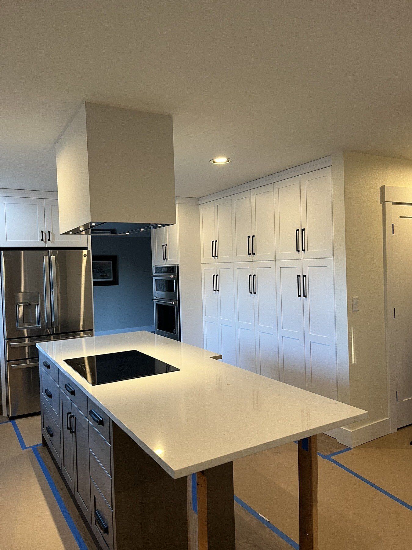 A kitchen with white cabinets , stainless steel appliances and a large island.