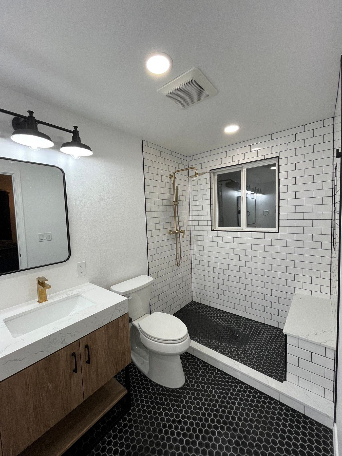 A bathroom with a toilet , sink , mirror and shower.