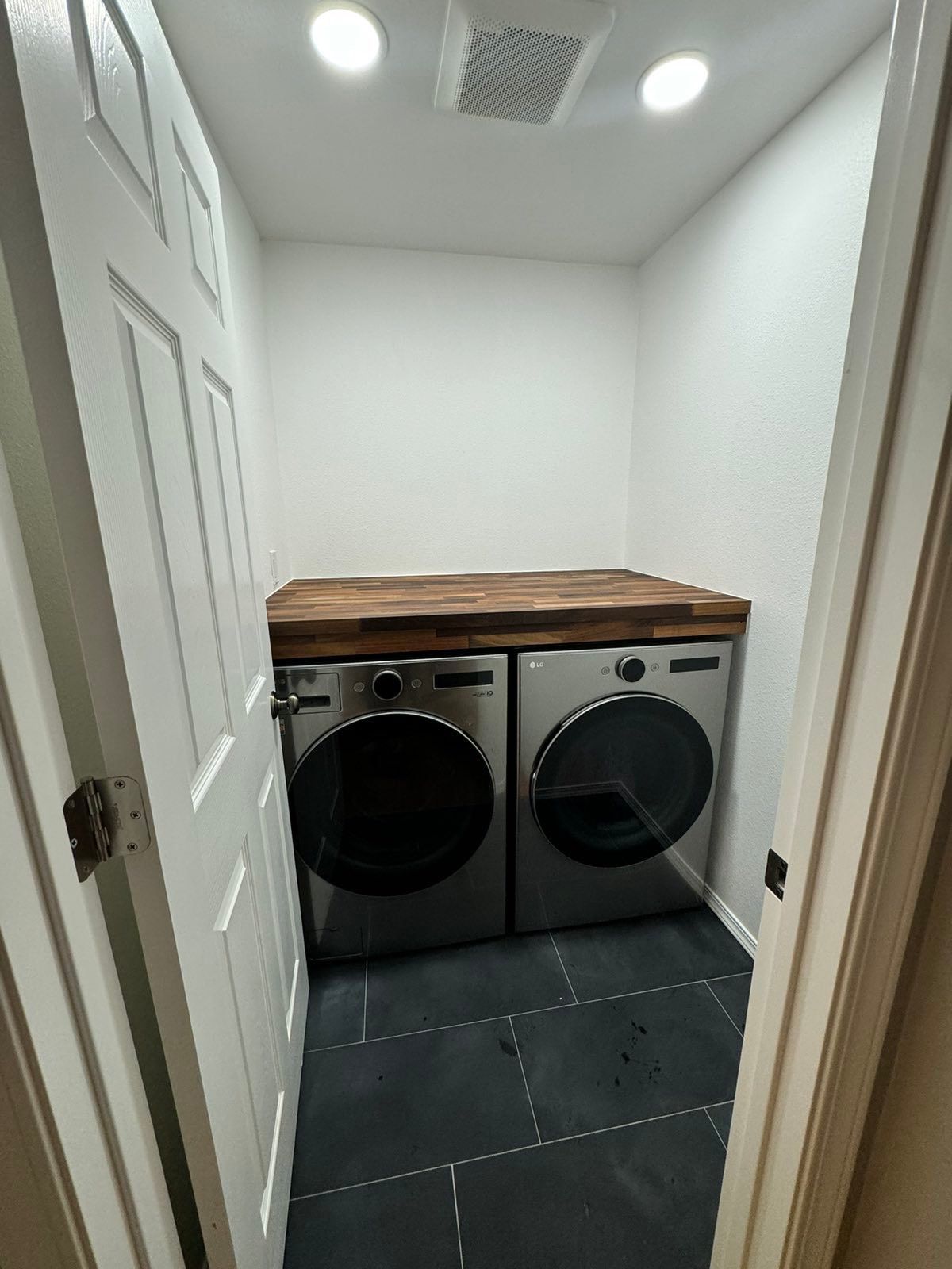 A laundry room with a washer and dryer and a wooden counter top.