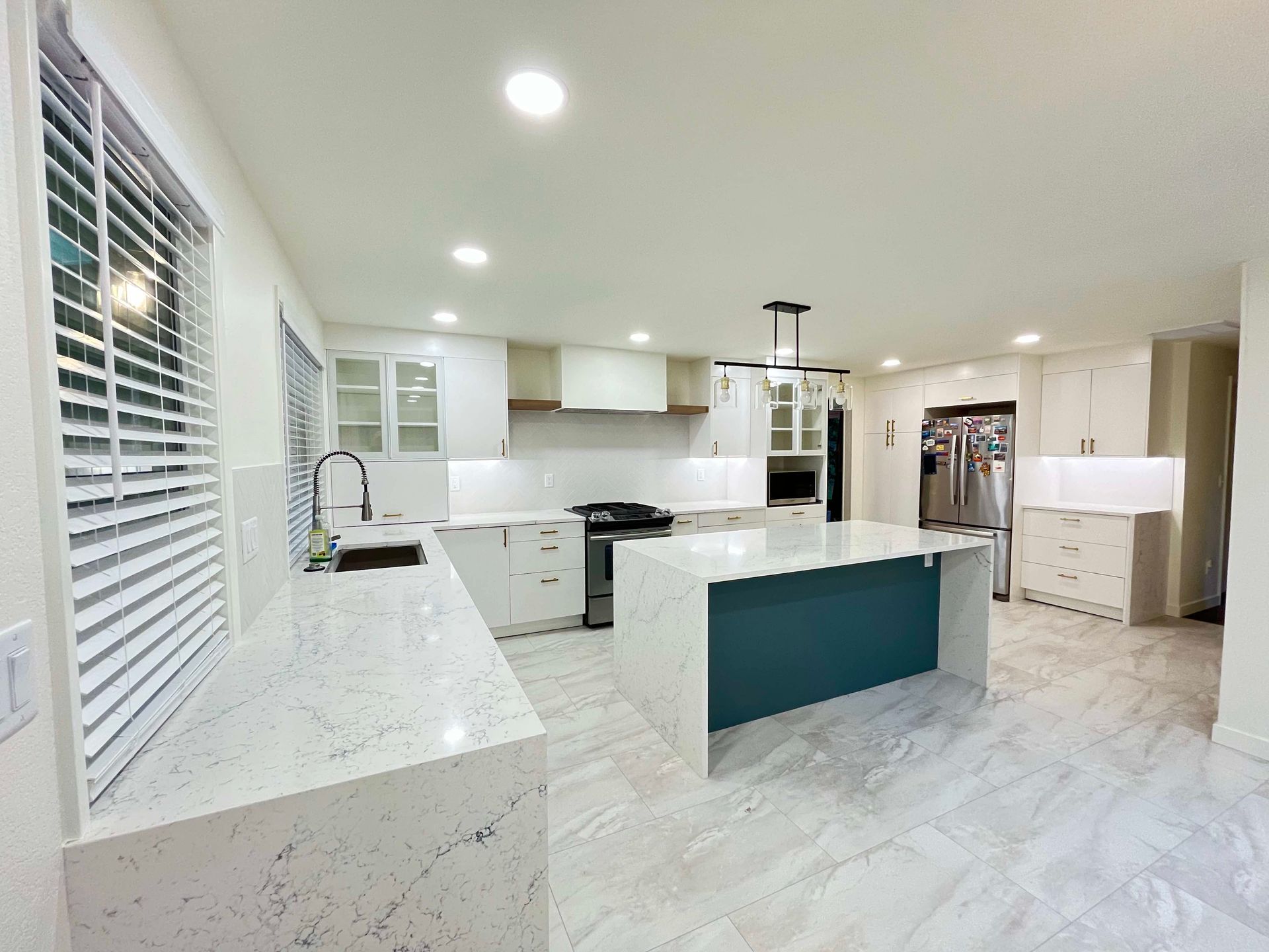A kitchen with white cabinets and a blue island.