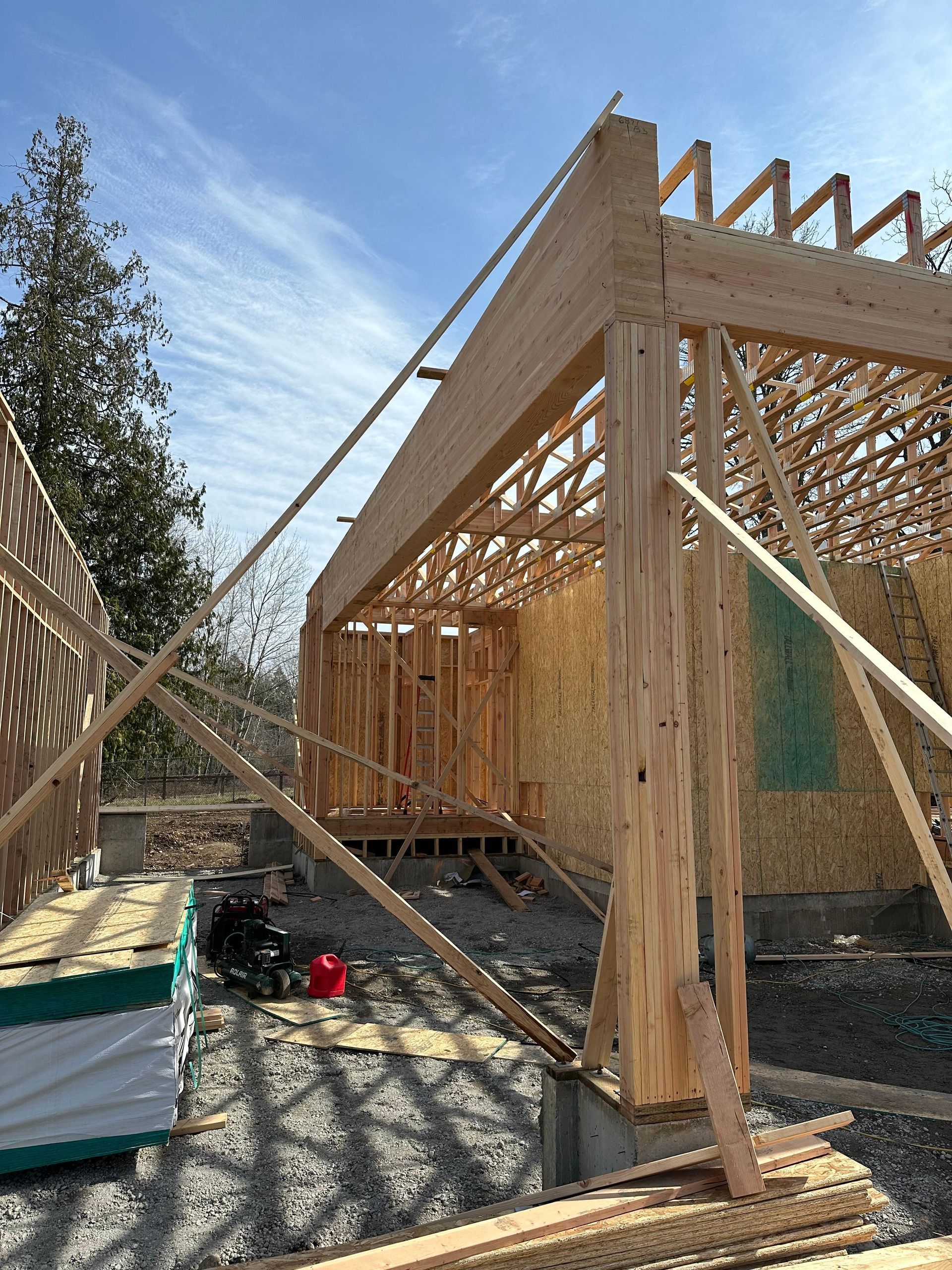 A house is being built with wooden beams and a blue sky in the background.