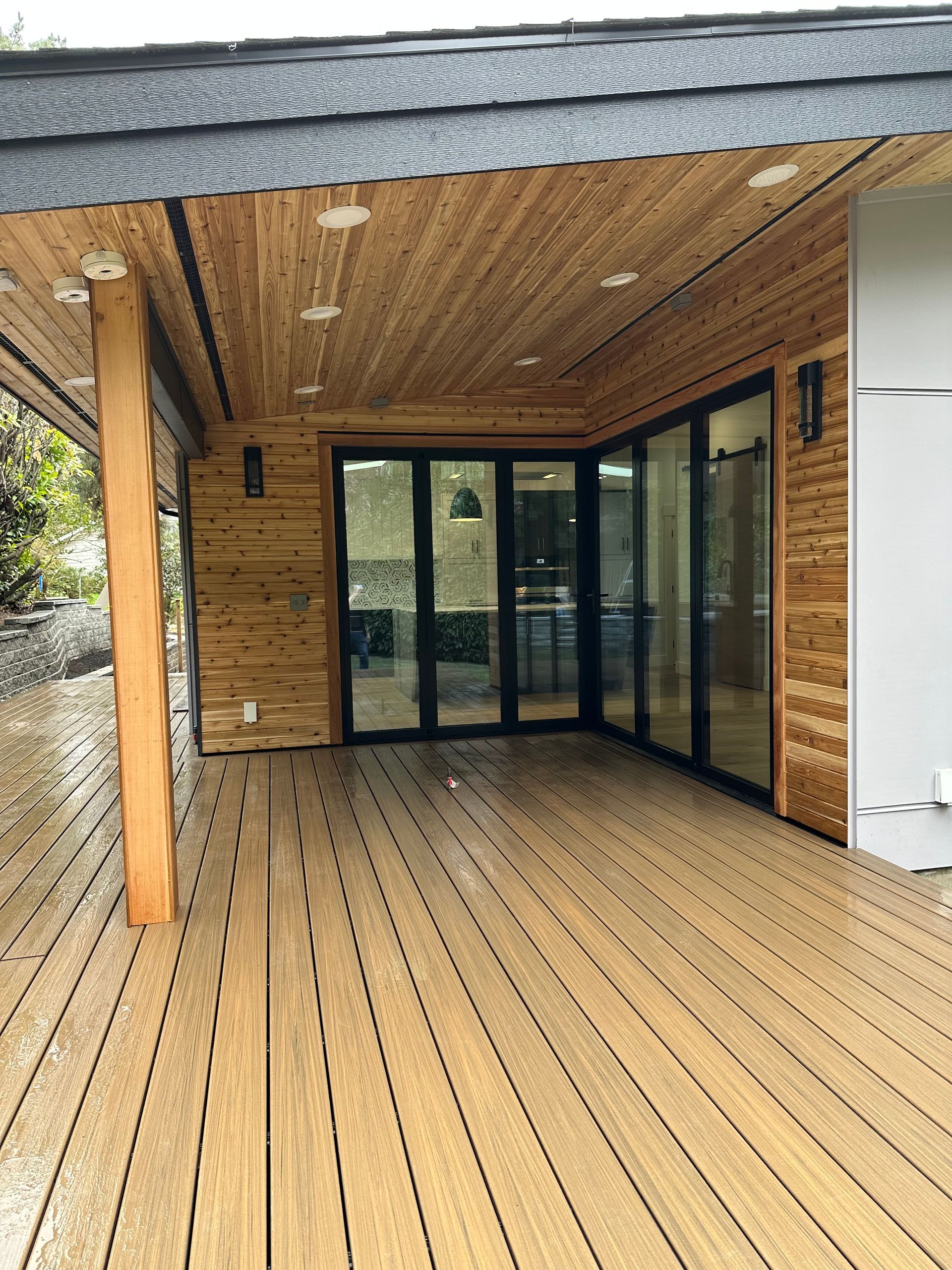 A large wooden deck with sliding glass doors and a roof.