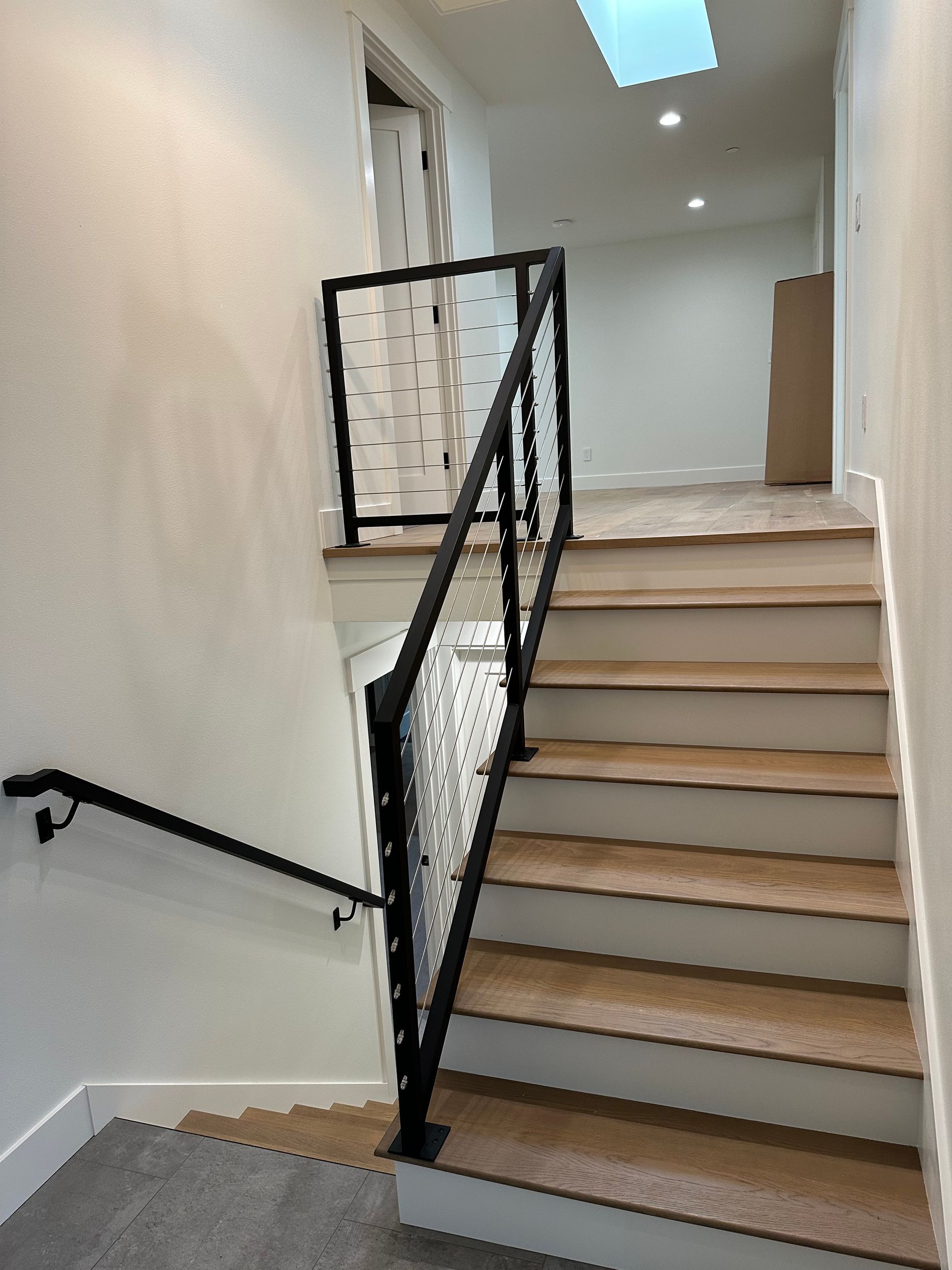 A staircase with a black railing and a skylight in the ceiling