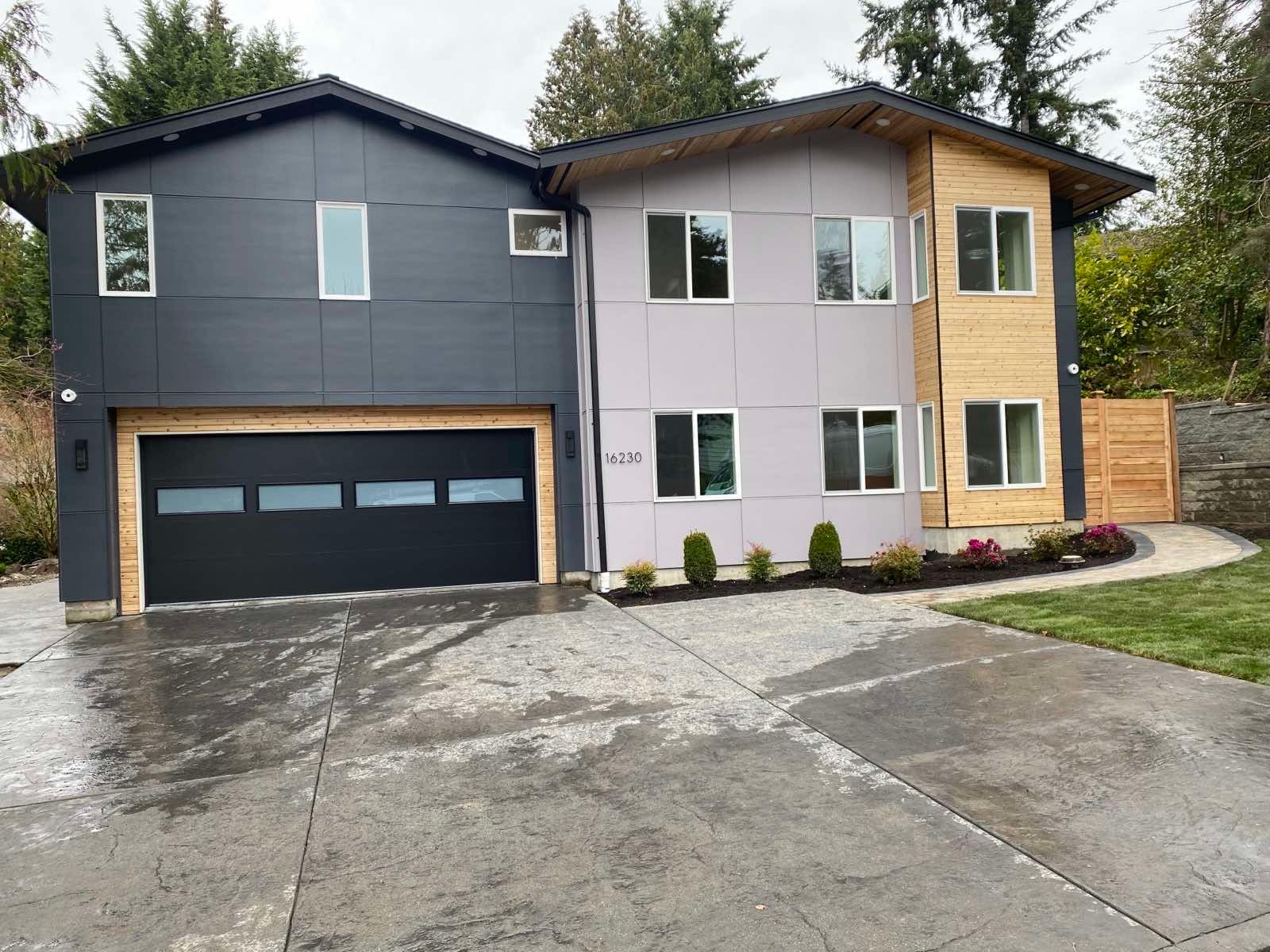 A large house with a black garage door and a lot of windows