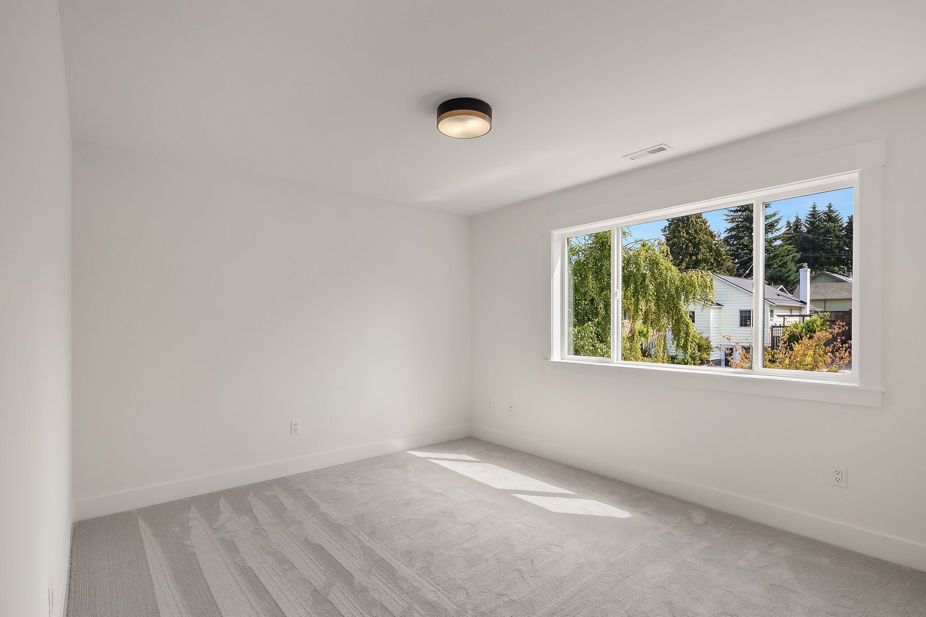 An empty bedroom with two windows and a ceiling light.