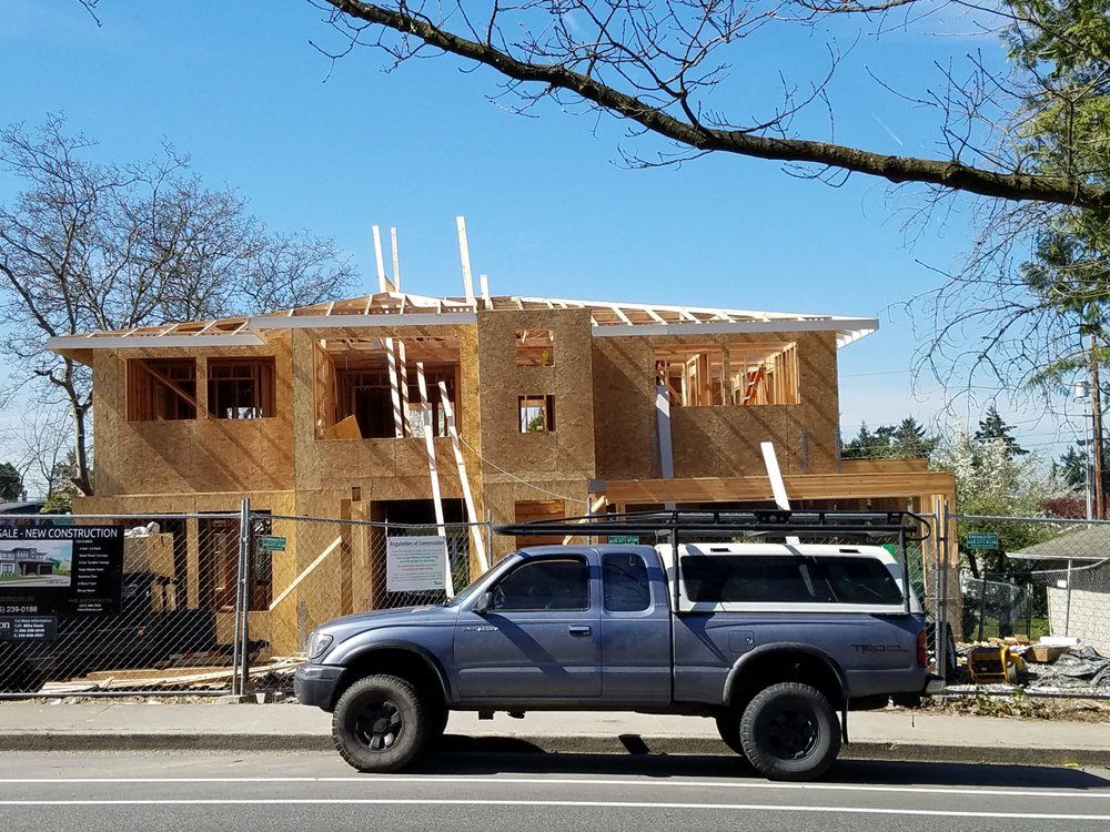 A truck is parked in front of a house under construction