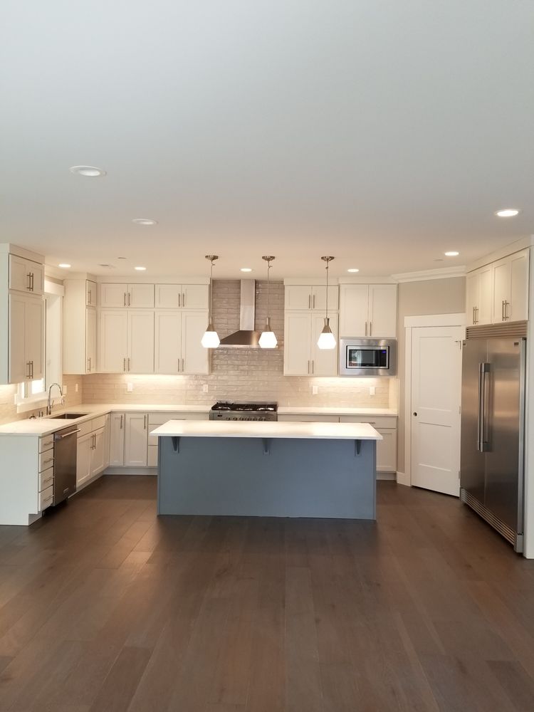 An empty kitchen with white cabinets and stainless steel appliances