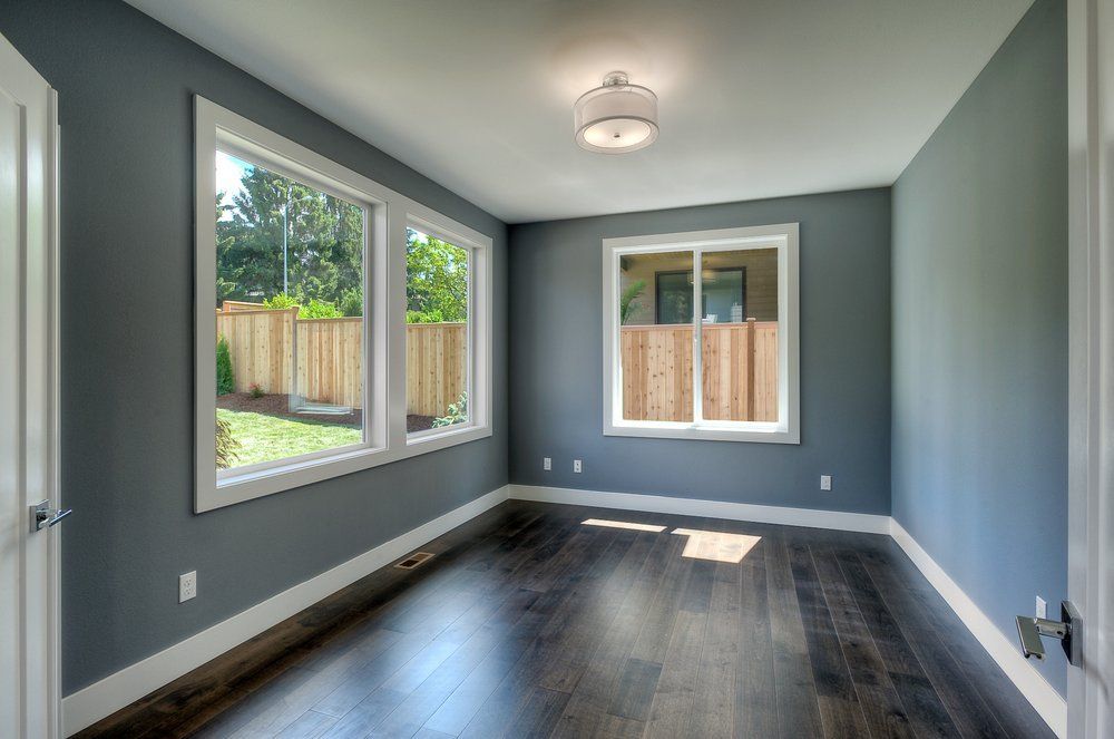 An empty room with gray walls and hardwood floors