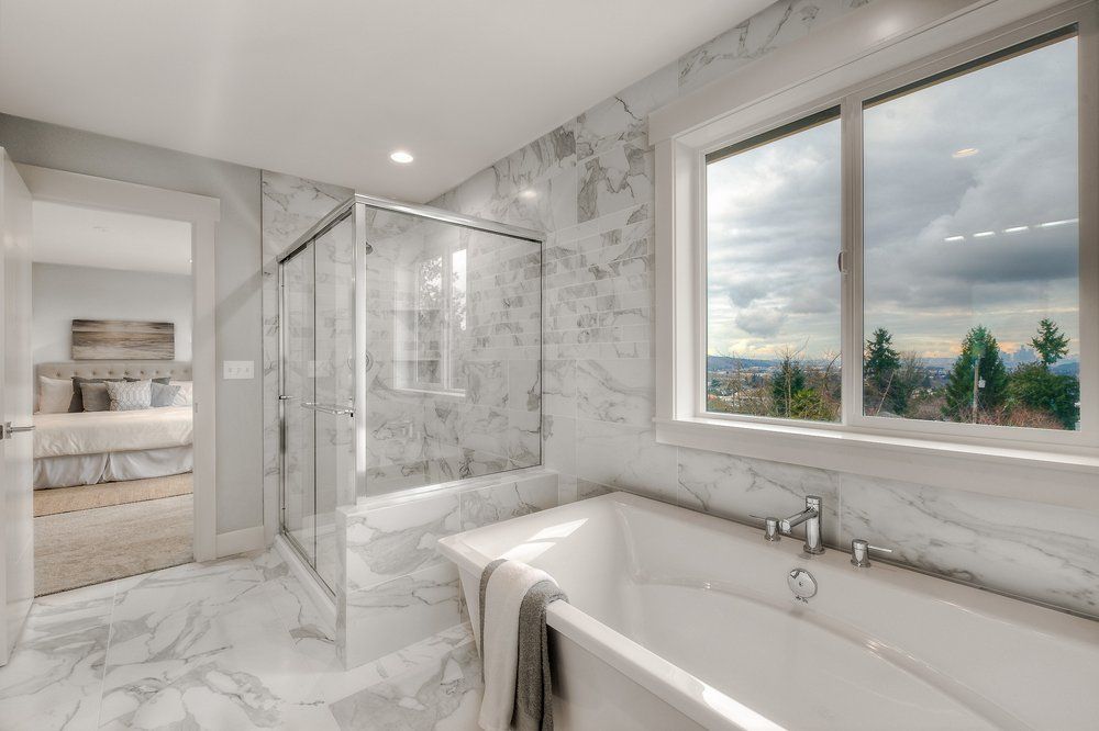 A bathroom with a tub , shower , and window.