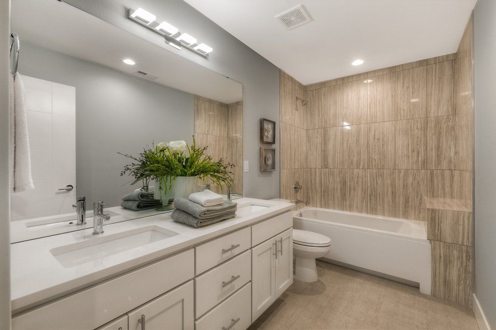 A bathroom with a sink , toilet , tub and mirror.