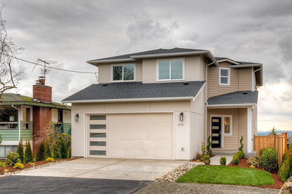 A white house with a gray roof and a black garage door