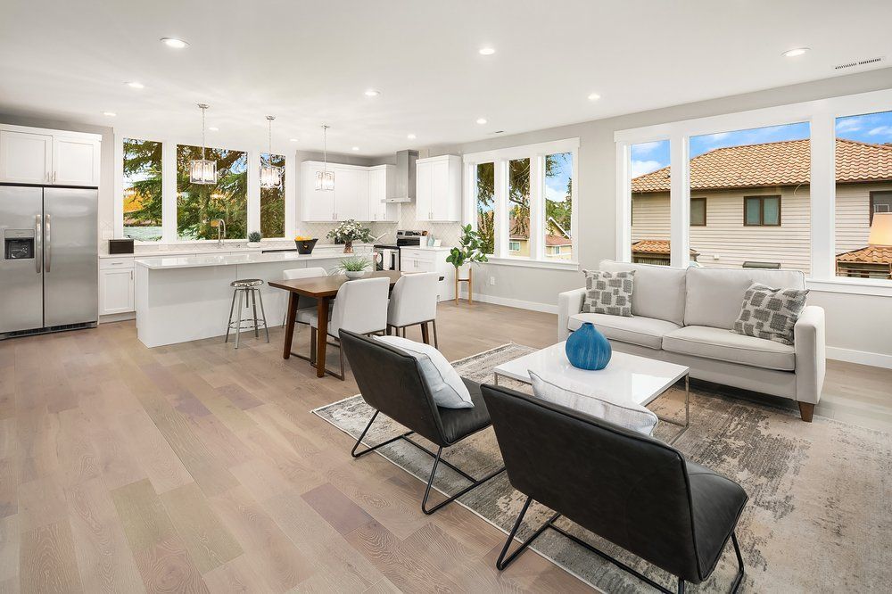 A living room with a couch , chairs , a table and a refrigerator.