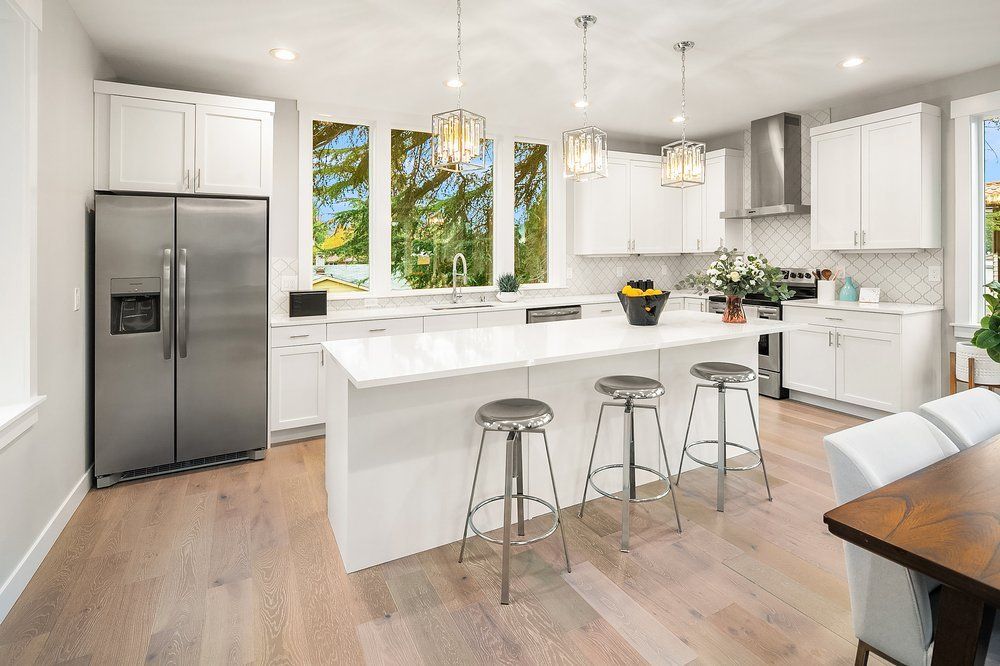 A kitchen with white cabinets , stainless steel appliances , and a large island.