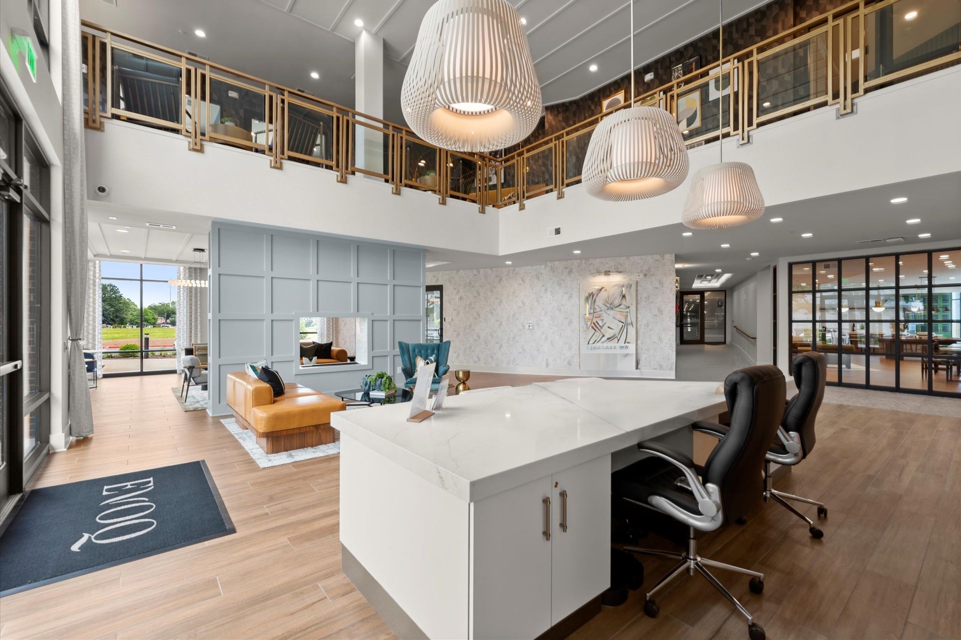 Modern lobby with white desk, orange sofa, and two-story balcony at EVOQ East Cobb Marietta, GA.