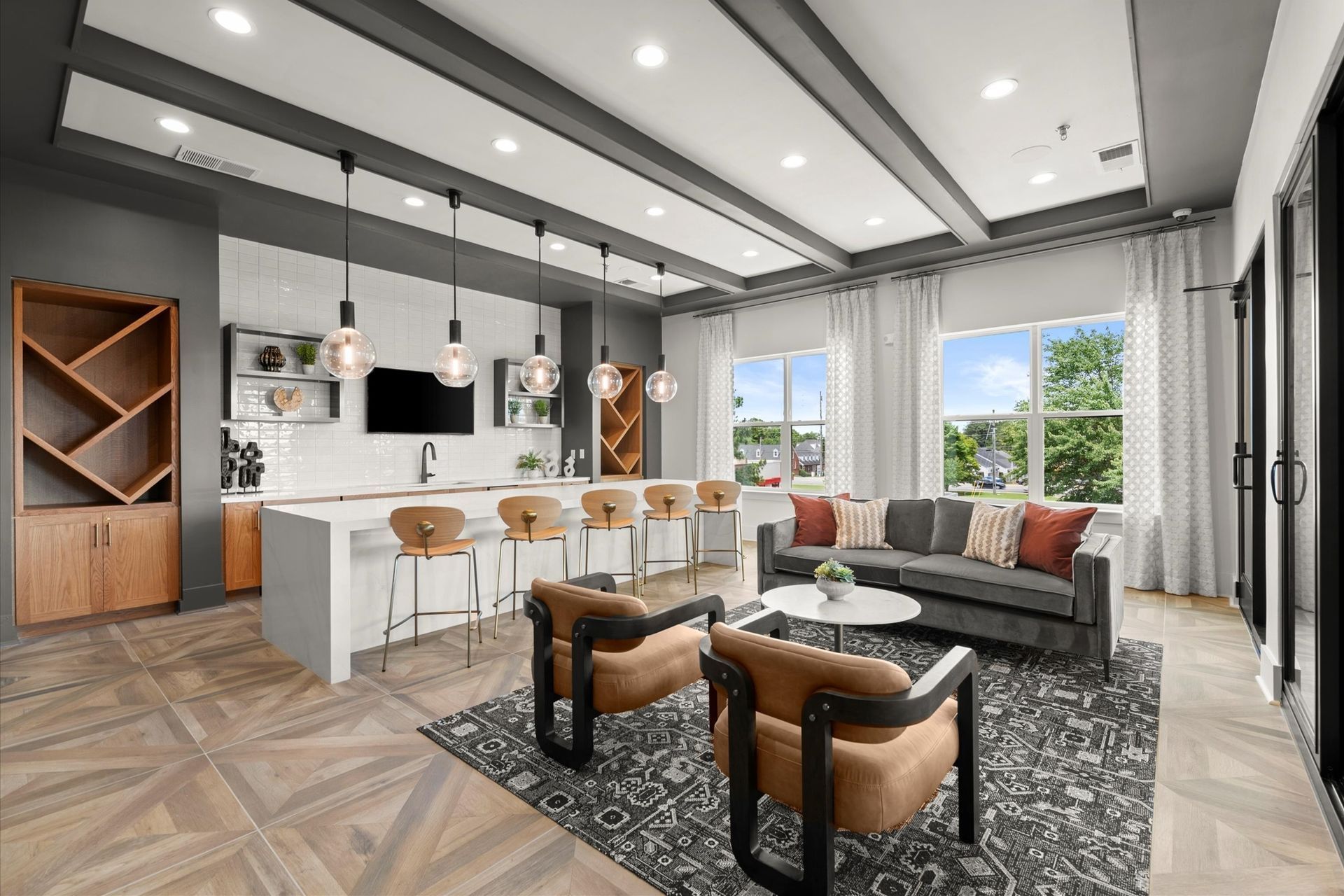 Modern apartment lounge with kitchen, seating area, and large windows; neutral colors, pendant lights at EVOQ