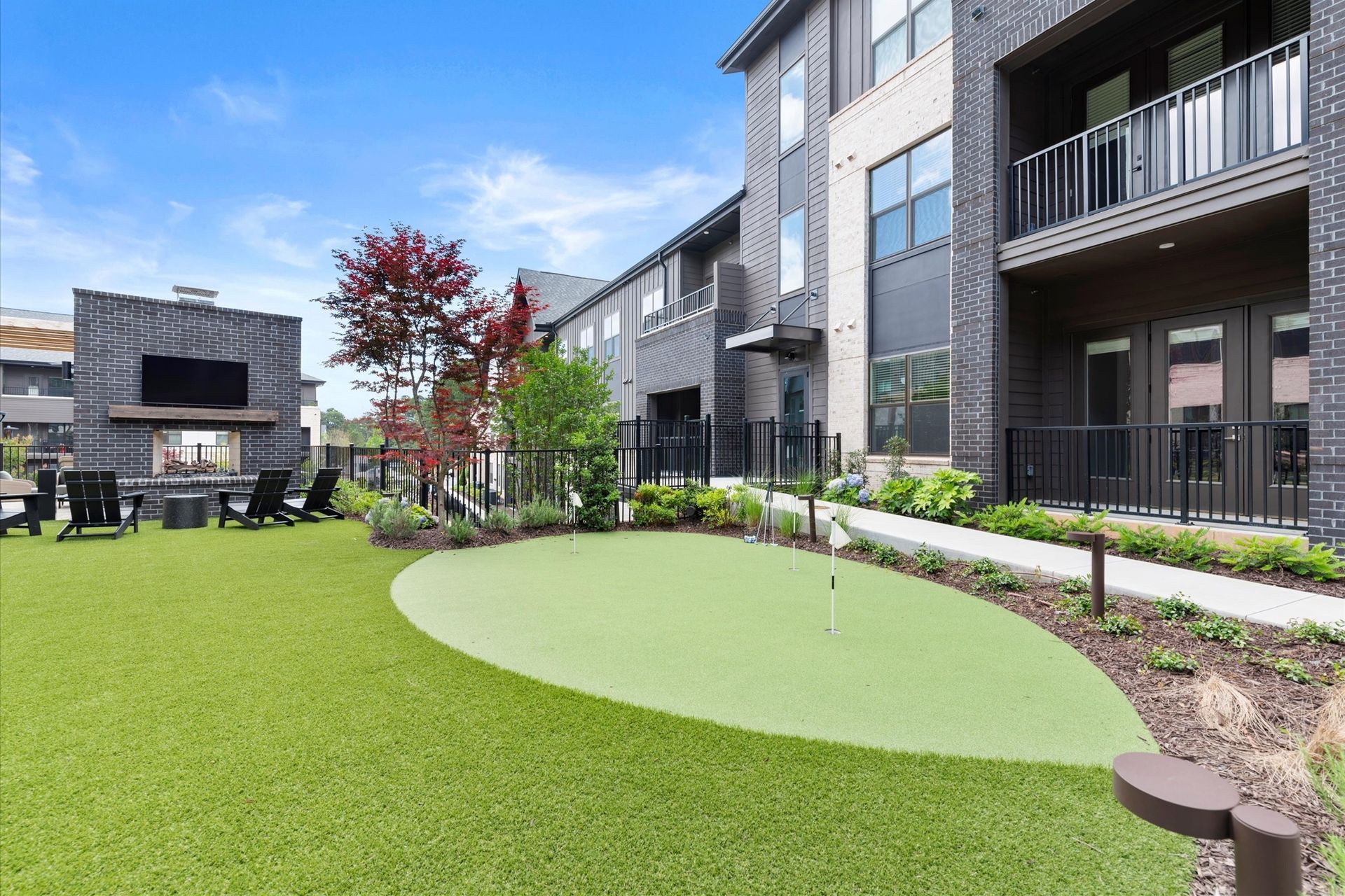 An outdoor recreation area with a putting green, fireplace, and apartment building at EVOQ