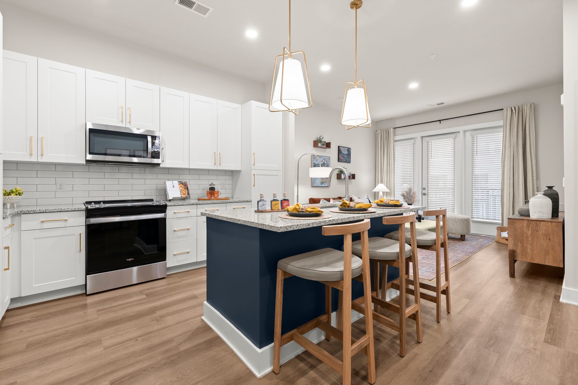 Kitchen interors featuring island with stools white cabinets and wood floors at EVOQ