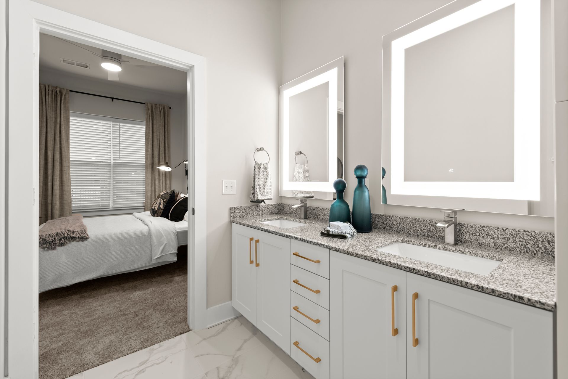 Bathroom with double vanity, two light-up mirrors, and an open doorway to a bedroom at EVOQ Marietta.