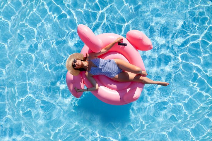Woman in a blue swimsuit and hat relaxes on a pink flamingo float in a blue pool at EVOQ East Cobb Marietta, GA.