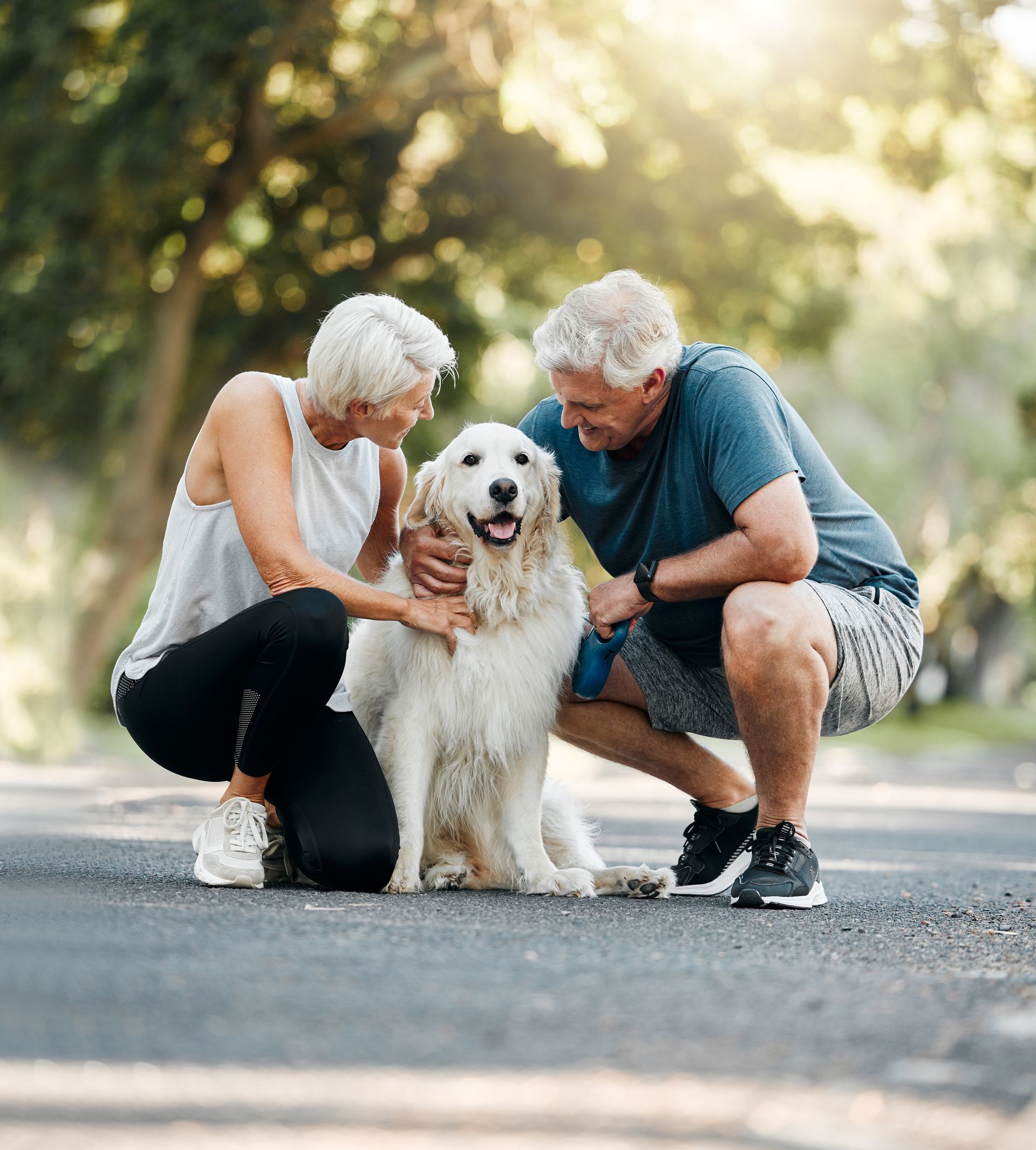 Couple petting a golden retriever on a paved path outdoors at EVOQ East Cobb Marietta, GA.