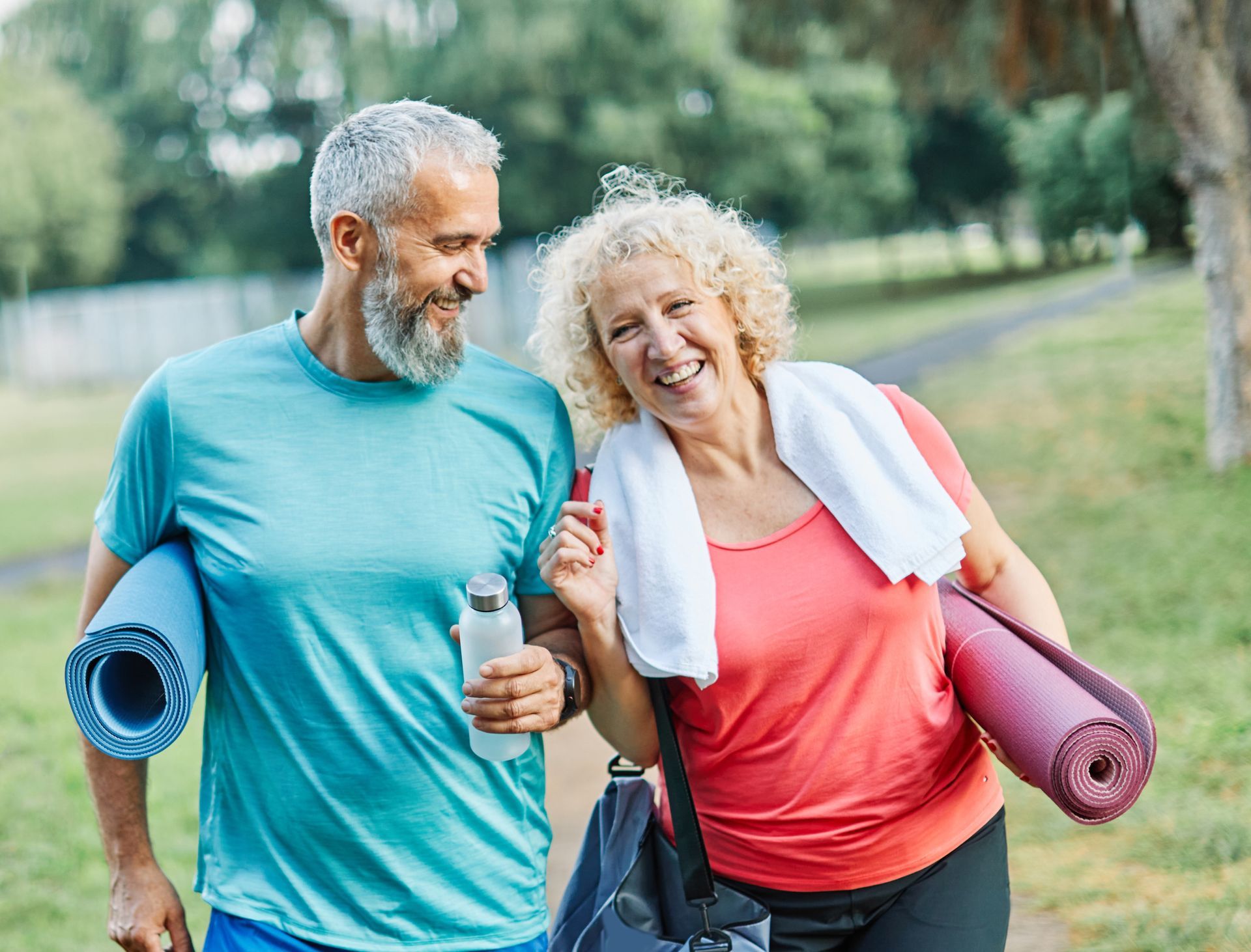 Couple walking outdoors, smiling, with yoga mats and water bottle at EVOQ East Cobb Marietta, GA.
